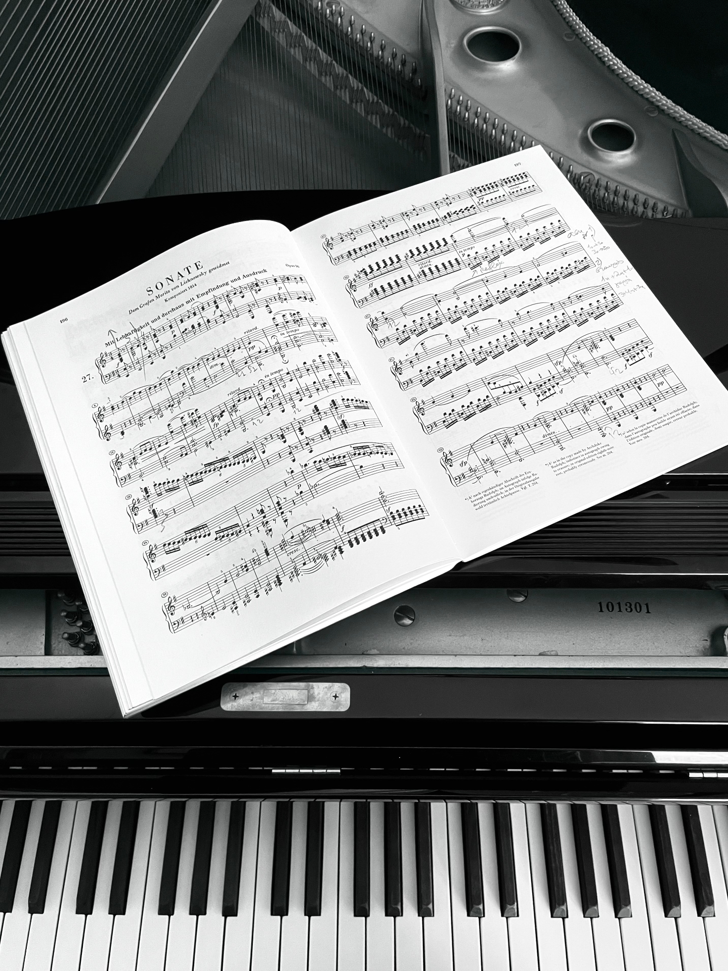 An open piano score resting on a grand piano, keys in the foreground